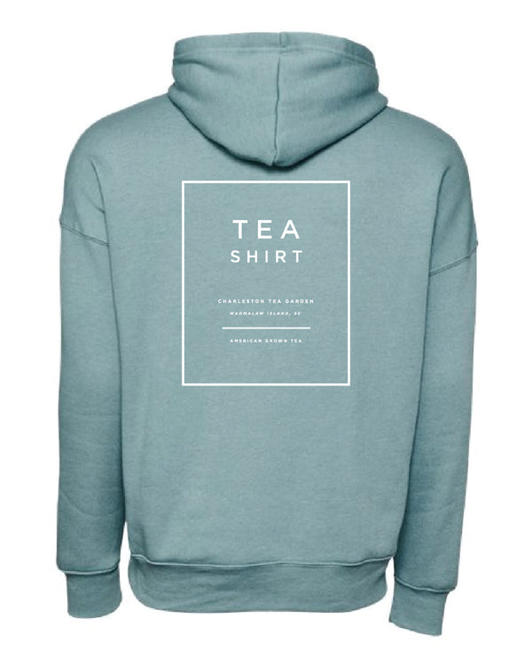 Back view of a soft blue fleece hoodie featuring white minimalist text promoting Charleston Tea Garden and American Classic Tea.