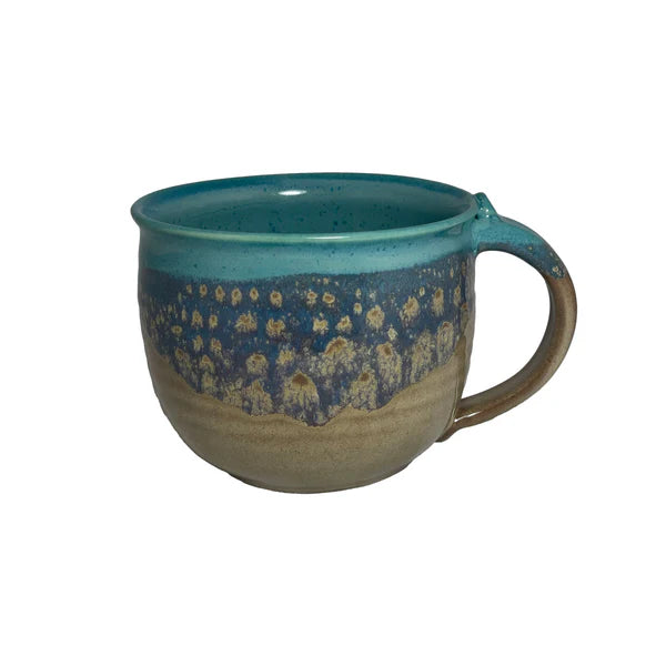 Ceramic latte mug with a blue and earthy-toned glaze, featuring a textured pattern inspired by natural island landscapes.