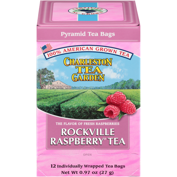 Pink box of Charleston Tea Garden’s Rockville Raspberry tea featuring fresh raspberries and an image of lush green tea fields under a blue sky.