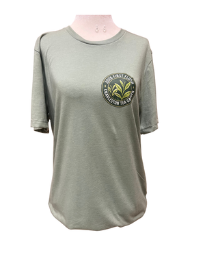 Light green casual t-shirt featuring a Charleston Tea Garden emblem with tea leaves and "2026 First Flush" text, perfect for tea lovers and souvenir apparel.