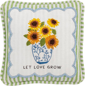 Square decorative pillow with embroidered sunflowers in a blue vase and the phrase "Let Love Grow," bordered by green and white striped fabric.