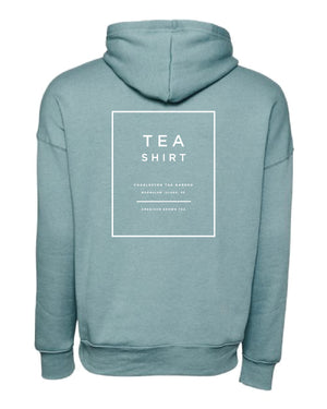 Back view of a soft blue fleece hoodie featuring white minimalist text promoting Charleston Tea Garden and American Classic Tea.