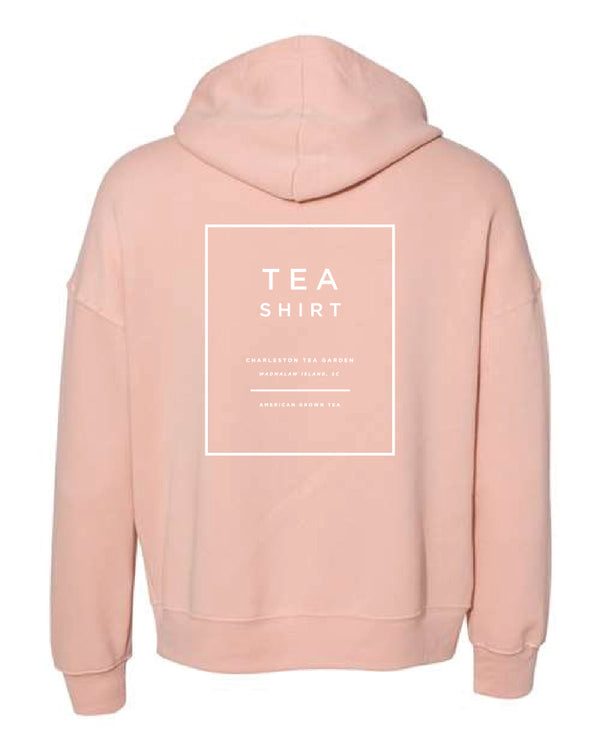 Back view of a soft peach fleece hoodie featuring a minimalist white box design promoting Charleston Tea Garden and American Classic Tea, perfect for casual wear or souvenirs.