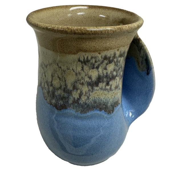 A ceramic handwarmer mug with a wide rim, featuring a sandy beige and blue glaze that mimics natural beach tones, perfect for cozy tea moments.