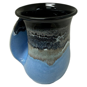 Ceramic handwarmer mug with a smooth blue and black glaze, designed for cozy tea moments and inspired by calming ocean hues.