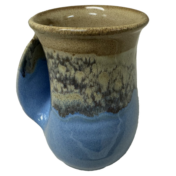 A ceramic handwarmer mug with a smooth, curved handle, featuring a sandy beige and ocean blue glaze that evokes a calm beach scene.