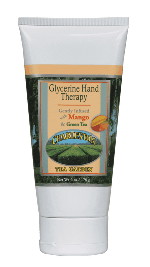 Tube of glycerine hand therapy lotion infused with mango and green tea, featuring Charleston Tea Garden branding and a scenic tea field illustration.