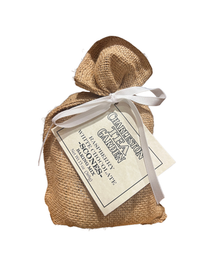 Small burlap sack tied with a white ribbon holding a package of raspberry white chocolate scone mix with a Charleston Tea Garden label.