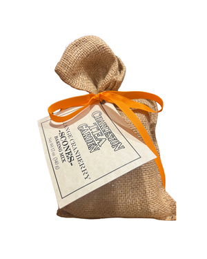 Small burlap sack tied with an orange ribbon containing baking mix, featuring a Charleston Tea Garden label for orange cranberry scones.