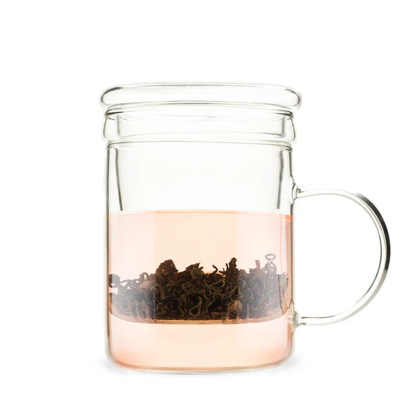 Clear glass mug with a built-in tea infuser steeping loose leaf tea, showcasing the warm pinkish hue of the brew.