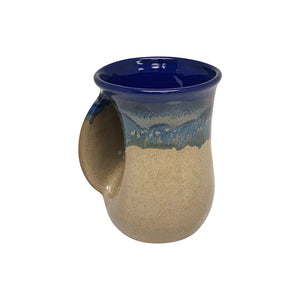 Ceramic handwarmer mug with a smooth cobalt blue interior and a natural beige exterior featuring a blue drip glaze, designed for comfortable warmth while sipping tea.