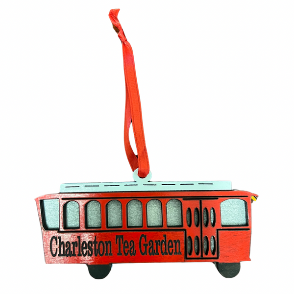 Red trolley ornament with black wheels and windows, featuring "Charleston Tea Garden" lettering and a red hanging ribbon, inspired by a classic Charleston tram.
