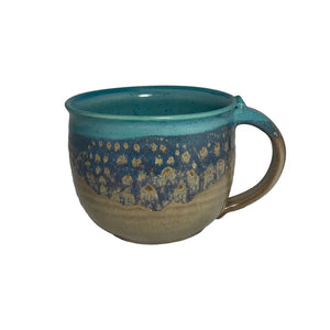 Ceramic latte mug with a blue and earthy-toned glaze, featuring a textured pattern inspired by natural island landscapes.