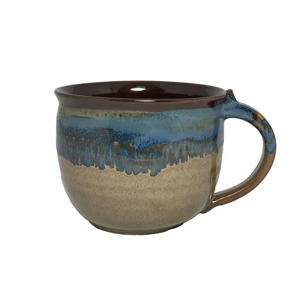 Handcrafted ceramic mug with a smooth beige base and a glossy blue and brown glaze dripping from the rim, perfect for enjoying a cozy latte or tea.