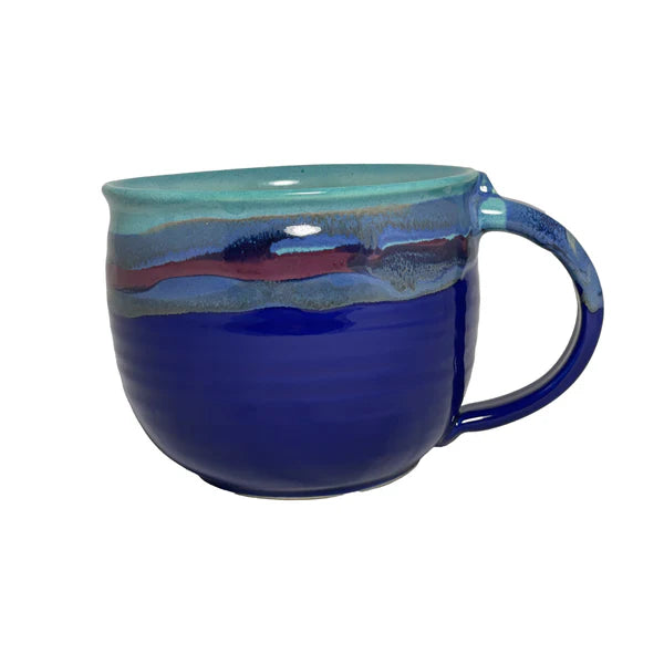 A ceramic latte mug with a deep blue base and a glossy, swirling pattern in shades of teal and purple around the rim and handle, perfect for enjoying a cozy cup.