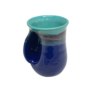 Ceramic handwarmer mug in deep blue and turquoise glaze with a curved pocket to warm hands while enjoying a hot beverage.