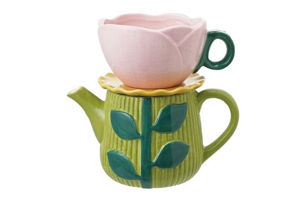 Ceramic teapot in green with leaf design, topped with a pink rose-shaped teacup and yellow saucer, perfect for a charming tea experience.