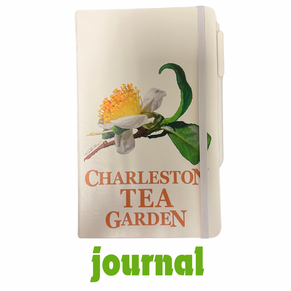 Journal with a detailed illustration of a tea flower and green leaves, featuring the words Charleston Tea Garden on the cover and a white elastic band closure.