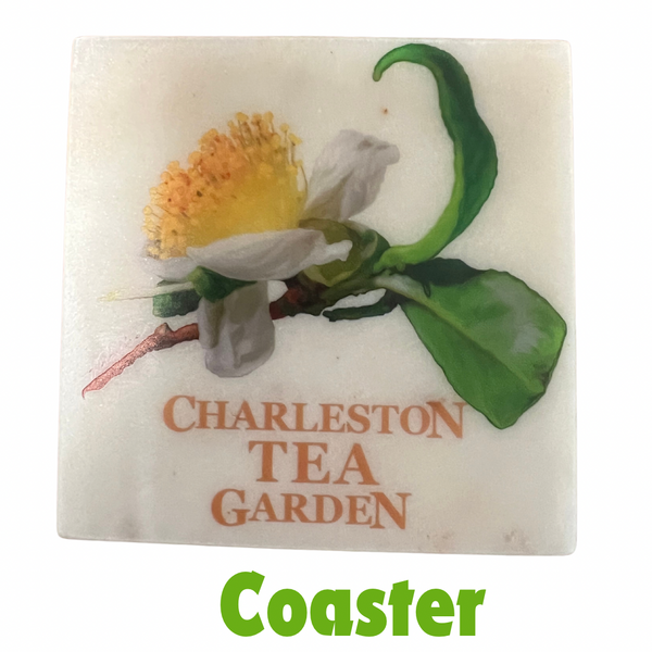 Square marble coaster featuring a detailed illustration of a tea flower with green leaves and the words "Charleston Tea Garden" in warm orange text.