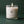 Lit white candle in a clear glass holder labeled with No. 17 Wadmalaw Island, featuring scents of white tea, berry, and ylang ylang against a dark green background.