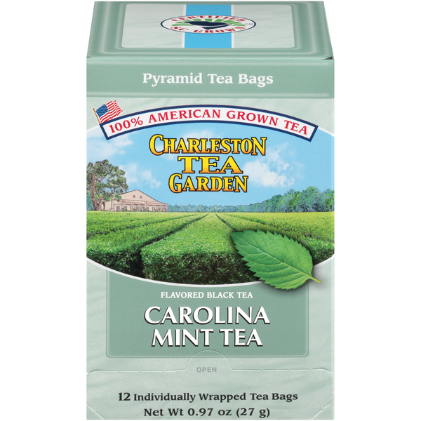 Box of Carolina Mint black tea featuring an illustration of a lush green tea field under a blue sky with a farmhouse in the background, emphasizing American-grown tea.