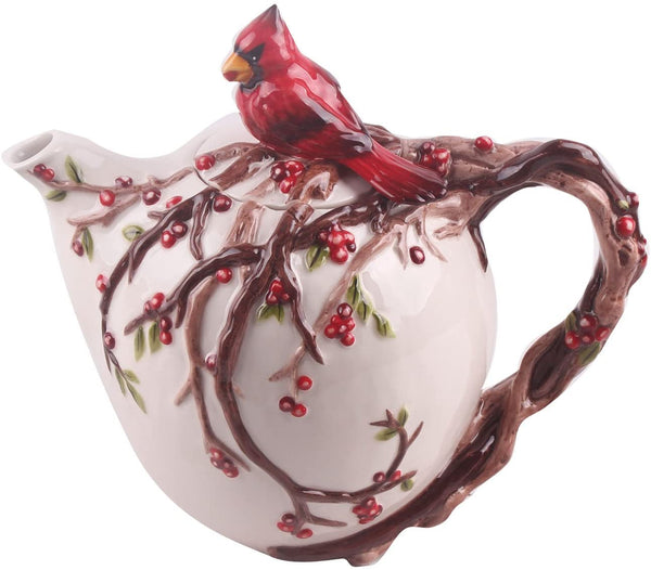 Ceramic teapot designed with intricate branches, red berries, and a bright red cardinal perched on top, blending nature-inspired art with functional use.