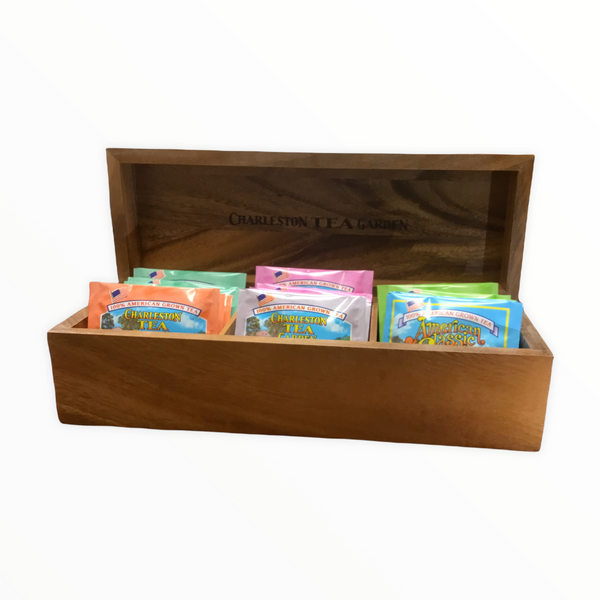 Open wooden tea chest displaying colorful assorted tea bags from Charleston Tea Garden, showcasing a warm, natural acacia wood finish.