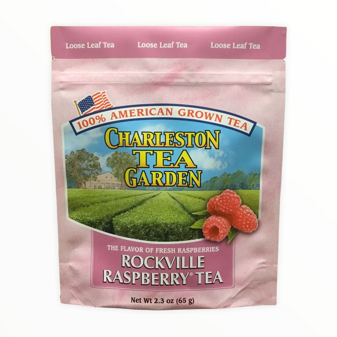 Pink pouch of loose leaf tea labeled Rockville Raspberry Tea from Charleston Tea Garden with an illustration of raspberry fruit and tea fields in the background.