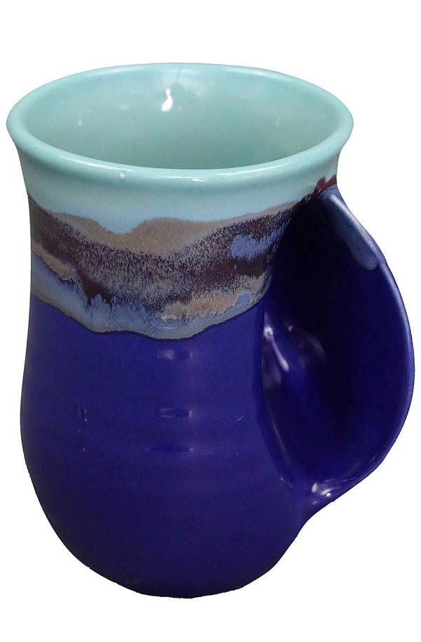 Handcrafted ceramic handwarmer mug in deep blue and soft teal with earthy glaze accents, designed for cozy comfort and warmth during tea time.